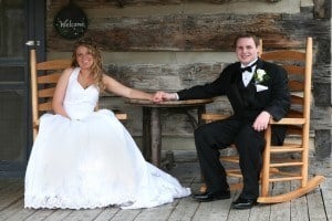 Happy bride and groom sitting on rocking chairs on the porch of their cabin.