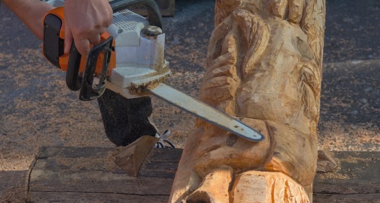 man using a chainsaw to carve